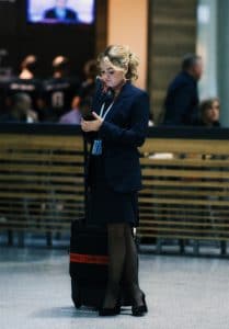 Flight attendant checks smartphone.